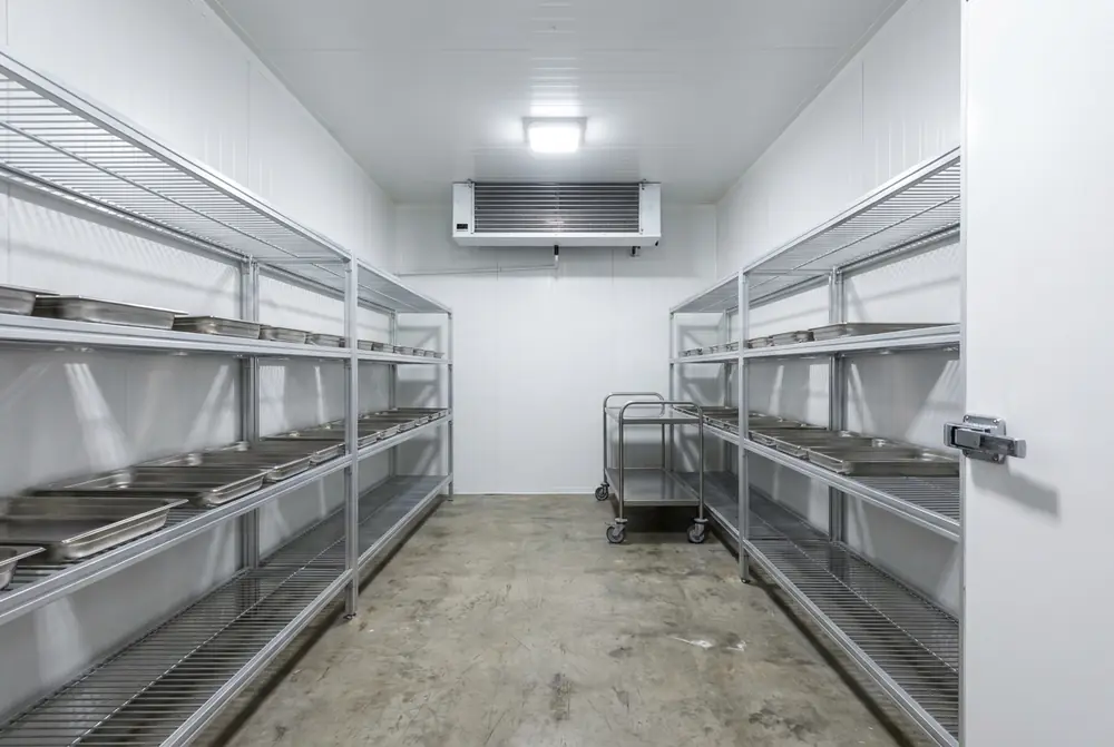 Empty new walk-in cool room with wire shelving down both sides and a clear aisle