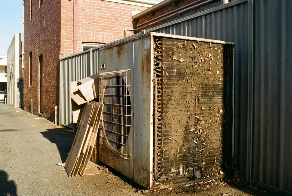Outdoor condensing unit with a clogged coil and cardboard stacked against it
