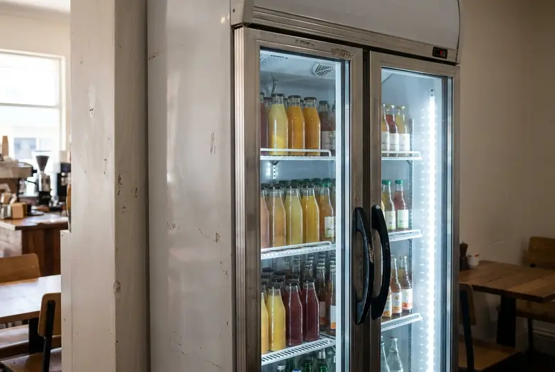 Double glass door display fridge stocked with bottled drinks in a cafe